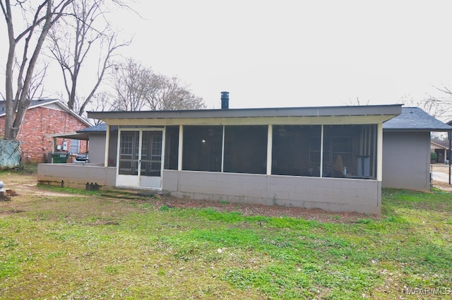 rear view of property featuring a sunroom and a lawn