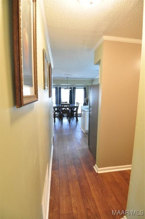 hallway featuring crown molding, dark hardwood / wood-style flooring, and a textured ceiling