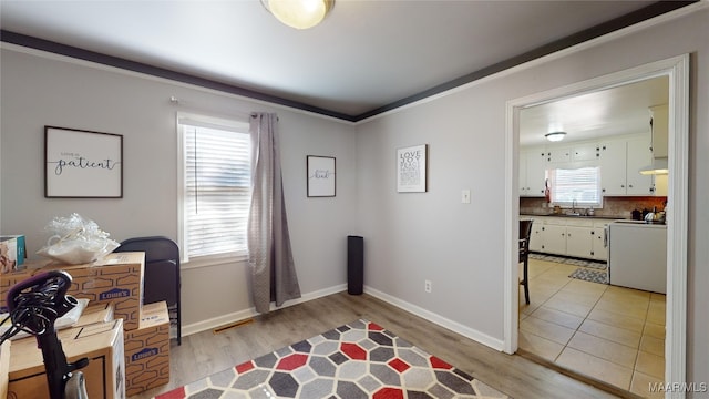 office space featuring ornamental molding, sink, and light hardwood / wood-style flooring