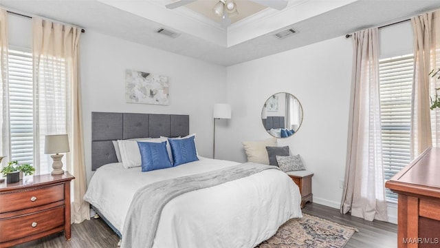 bedroom featuring crown molding, ceiling fan, a tray ceiling, and dark hardwood / wood-style flooring