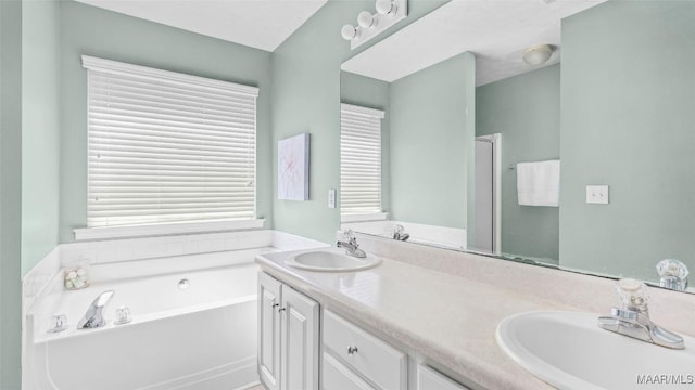 bathroom with a healthy amount of sunlight, a tub to relax in, and vanity