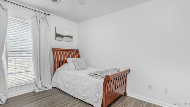 bedroom featuring ceiling fan, wood-type flooring, and a textured ceiling