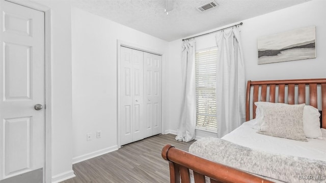 bedroom featuring ceiling fan, wood-type flooring, a closet, and a textured ceiling