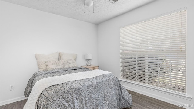 bedroom with ceiling fan, dark wood-type flooring, and a textured ceiling