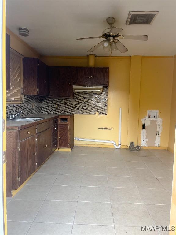 kitchen featuring dark brown cabinetry, backsplash, and light tile patterned floors