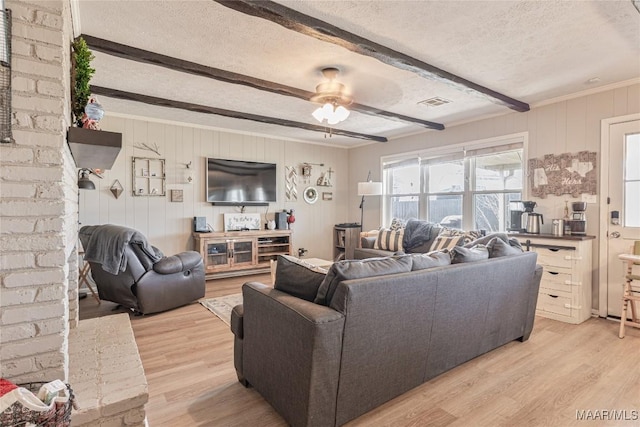 living room featuring beamed ceiling, ceiling fan, a textured ceiling, and light hardwood / wood-style floors