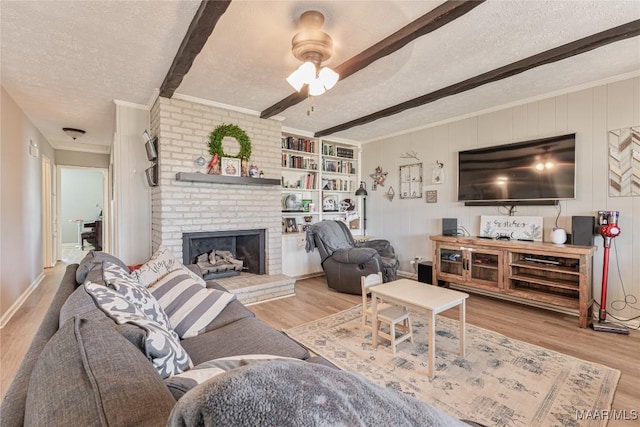 living room with a fireplace, beam ceiling, a textured ceiling, and light wood-type flooring