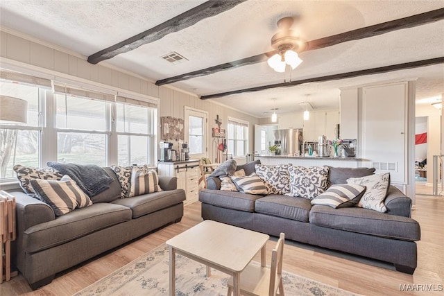 living room with ceiling fan, beam ceiling, a textured ceiling, and light hardwood / wood-style flooring