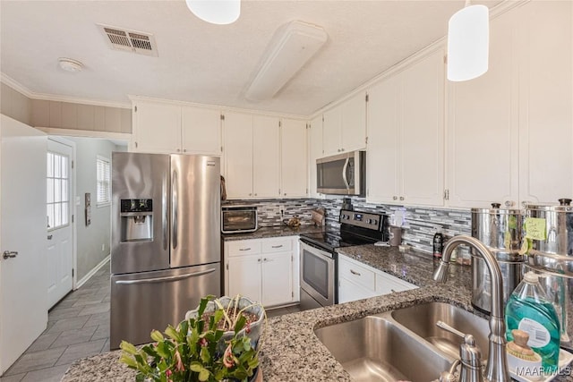 kitchen with sink, stone counters, appliances with stainless steel finishes, white cabinets, and backsplash