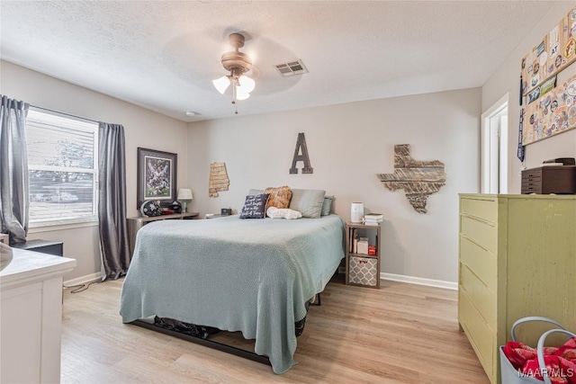 bedroom featuring ceiling fan, light hardwood / wood-style flooring, and a textured ceiling