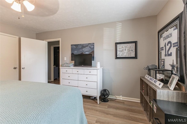 bedroom featuring ceiling fan, light hardwood / wood-style floors, and a textured ceiling