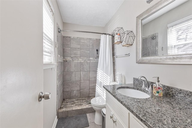 bathroom featuring vanity, a textured ceiling, toilet, and walk in shower