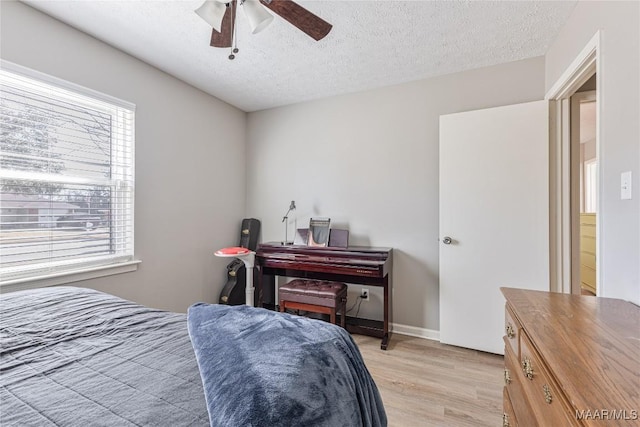 bedroom featuring ceiling fan, light hardwood / wood-style flooring, and a textured ceiling