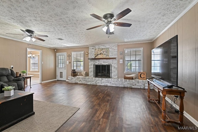 living room with a fireplace, dark hardwood / wood-style flooring, ornamental molding, ceiling fan, and a textured ceiling