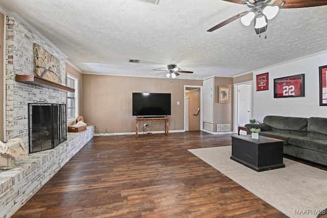 living room with a textured ceiling, ornamental molding, dark hardwood / wood-style floors, ceiling fan, and a fireplace