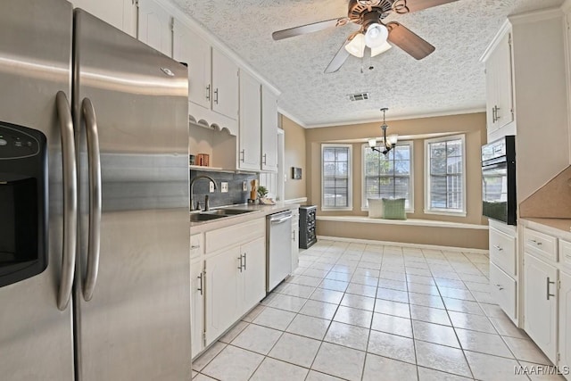 kitchen featuring white cabinetry, sink, hanging light fixtures, light tile patterned floors, and stainless steel appliances