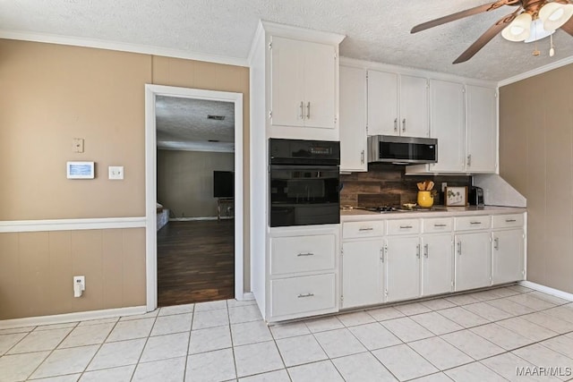 kitchen with stainless steel appliances, white cabinetry, ornamental molding, and light tile patterned flooring