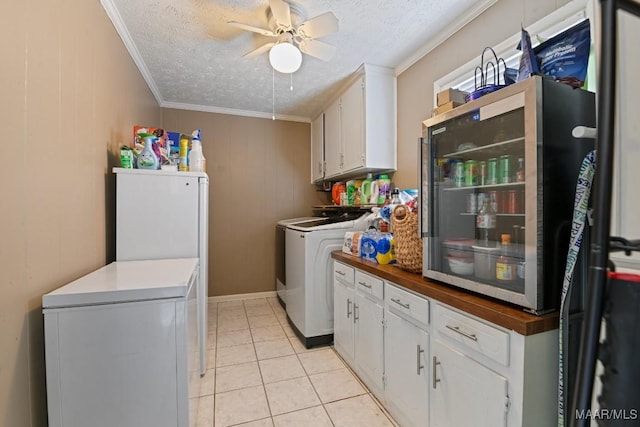 clothes washing area with light tile patterned flooring, separate washer and dryer, cabinets, ornamental molding, and a textured ceiling