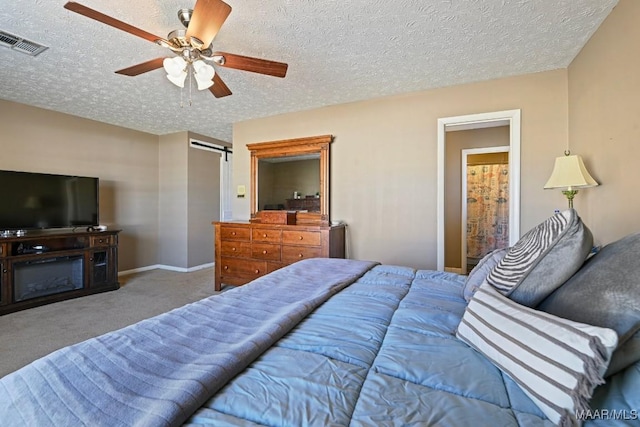 bedroom featuring ceiling fan, a barn door, carpet, and a textured ceiling