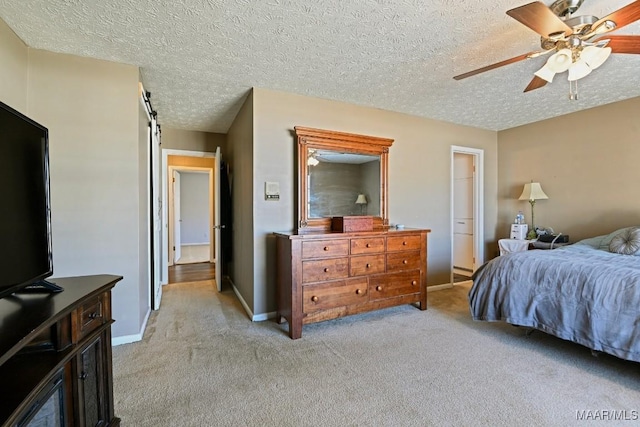 carpeted bedroom featuring a textured ceiling, a barn door, and ceiling fan