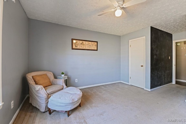 sitting room featuring ceiling fan, light colored carpet, and a textured ceiling