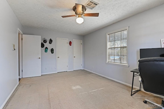 unfurnished office with ceiling fan, light carpet, and a textured ceiling