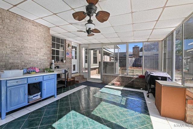 unfurnished sunroom with a drop ceiling and ceiling fan