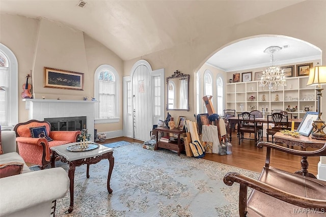 living room featuring hardwood / wood-style flooring, vaulted ceiling, a chandelier, and a tiled fireplace