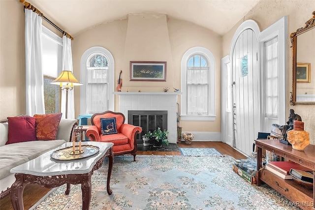 sitting room featuring hardwood / wood-style flooring, vaulted ceiling, and a tile fireplace