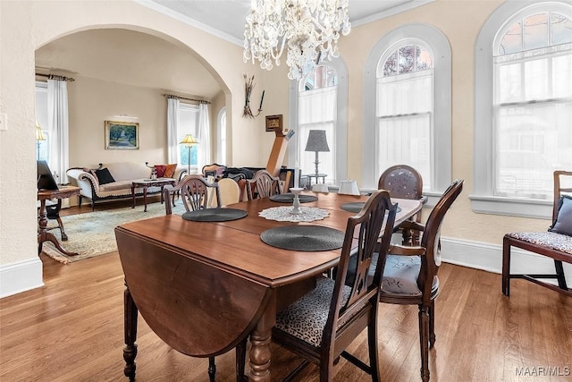 dining space with ornamental molding, a notable chandelier, and light hardwood / wood-style floors