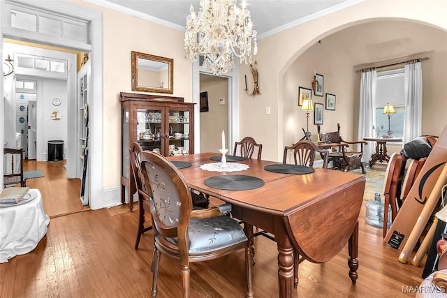 dining space featuring an inviting chandelier, crown molding, and light wood-type flooring