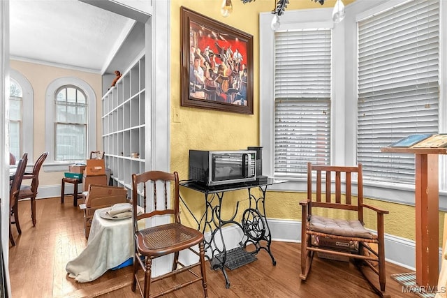 living area featuring wood-type flooring and crown molding