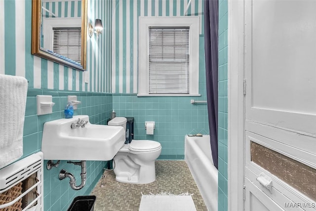 bathroom with a washtub, tile patterned flooring, tile walls, and toilet