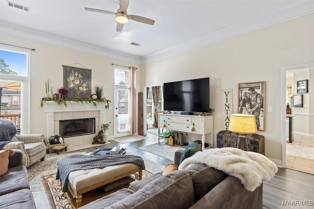 living room featuring hardwood / wood-style floors, crown molding, a fireplace, and ceiling fan