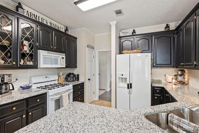 kitchen featuring light stone counters, white appliances, ornamental molding, and a textured ceiling