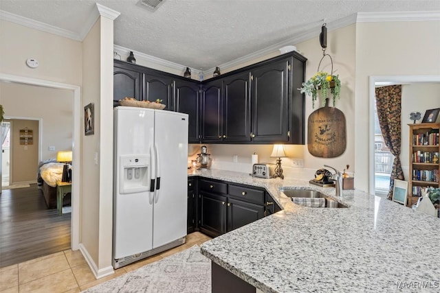 kitchen featuring ornamental molding, white refrigerator with ice dispenser, sink, and light stone countertops