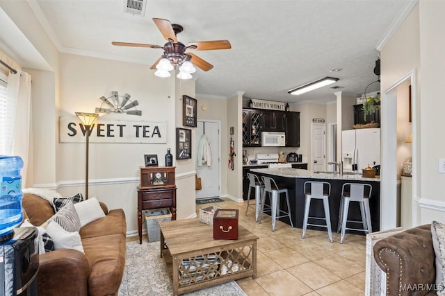 tiled living room with ceiling fan, ornamental molding, and sink