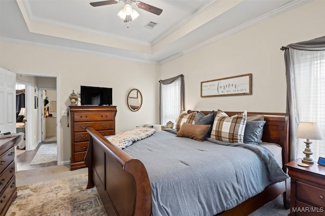 bedroom with ornamental molding, light colored carpet, a raised ceiling, and ceiling fan