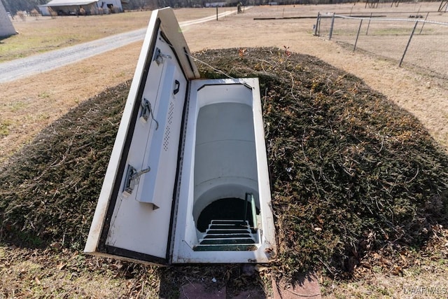 entry to storm shelter featuring a rural view