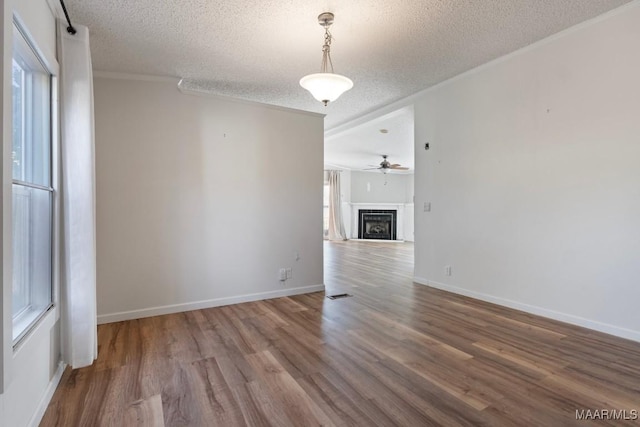 unfurnished living room featuring ornamental molding, hardwood / wood-style floors, ceiling fan, and a textured ceiling