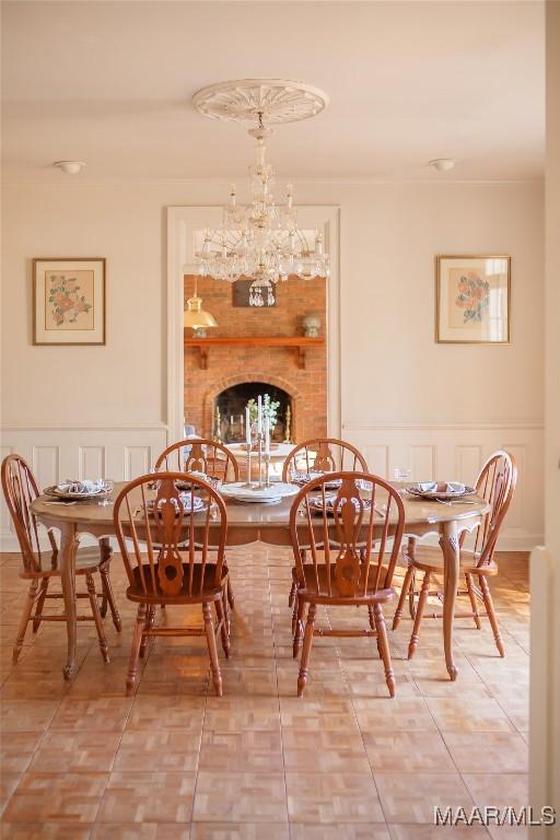 dining room featuring a brick fireplace, tile patterned floors, and a chandelier