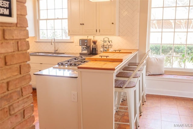 kitchen with tasteful backsplash, a healthy amount of sunlight, butcher block counters, and sink