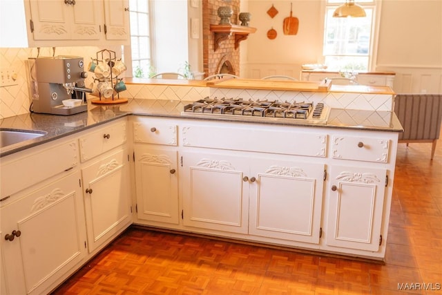 kitchen with tasteful backsplash, white cabinets, a wealth of natural light, and light parquet flooring