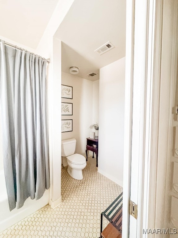 bathroom with shower / tub combo with curtain and toilet