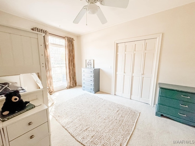 bedroom featuring crown molding, ceiling fan, light colored carpet, and a closet