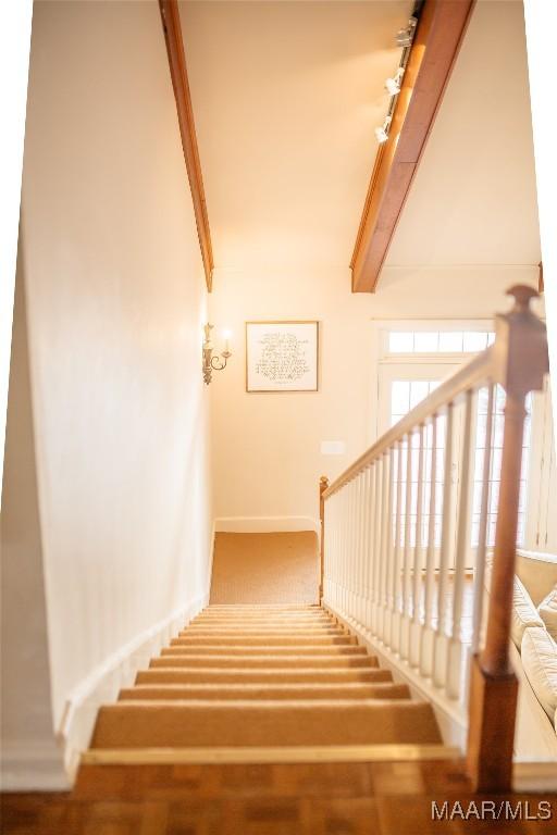 stairs with hardwood / wood-style floors and beam ceiling