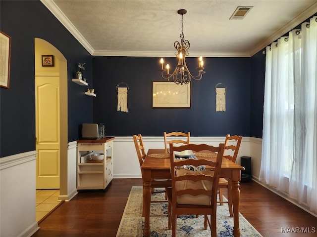 dining area with crown molding, dark hardwood / wood-style flooring, and a chandelier