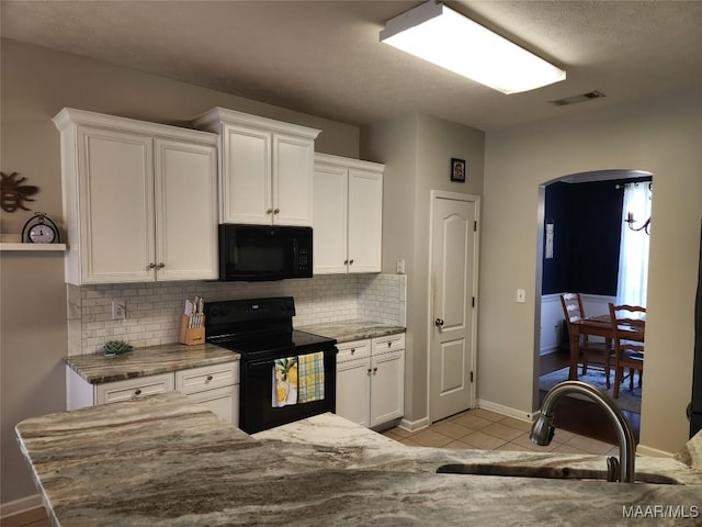 kitchen featuring sink, light tile patterned floors, white cabinetry, black appliances, and decorative backsplash