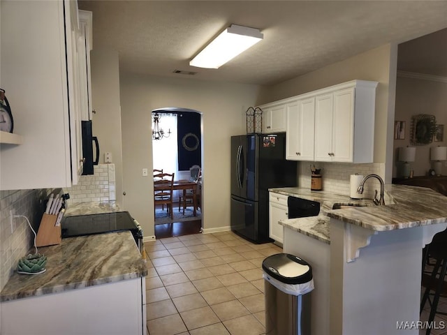 kitchen featuring light tile patterned flooring, sink, a kitchen breakfast bar, white cabinets, and black appliances