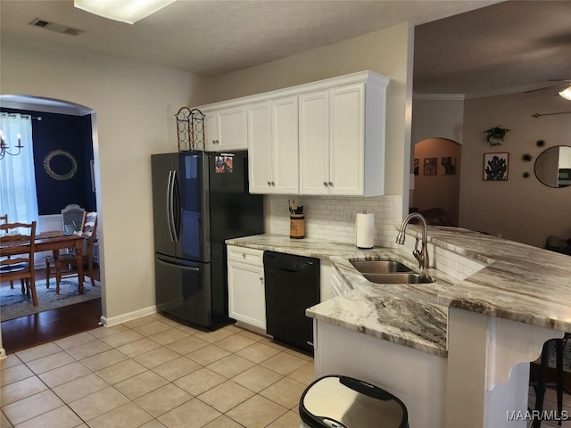 kitchen featuring kitchen peninsula, white cabinets, light stone counters, and black appliances